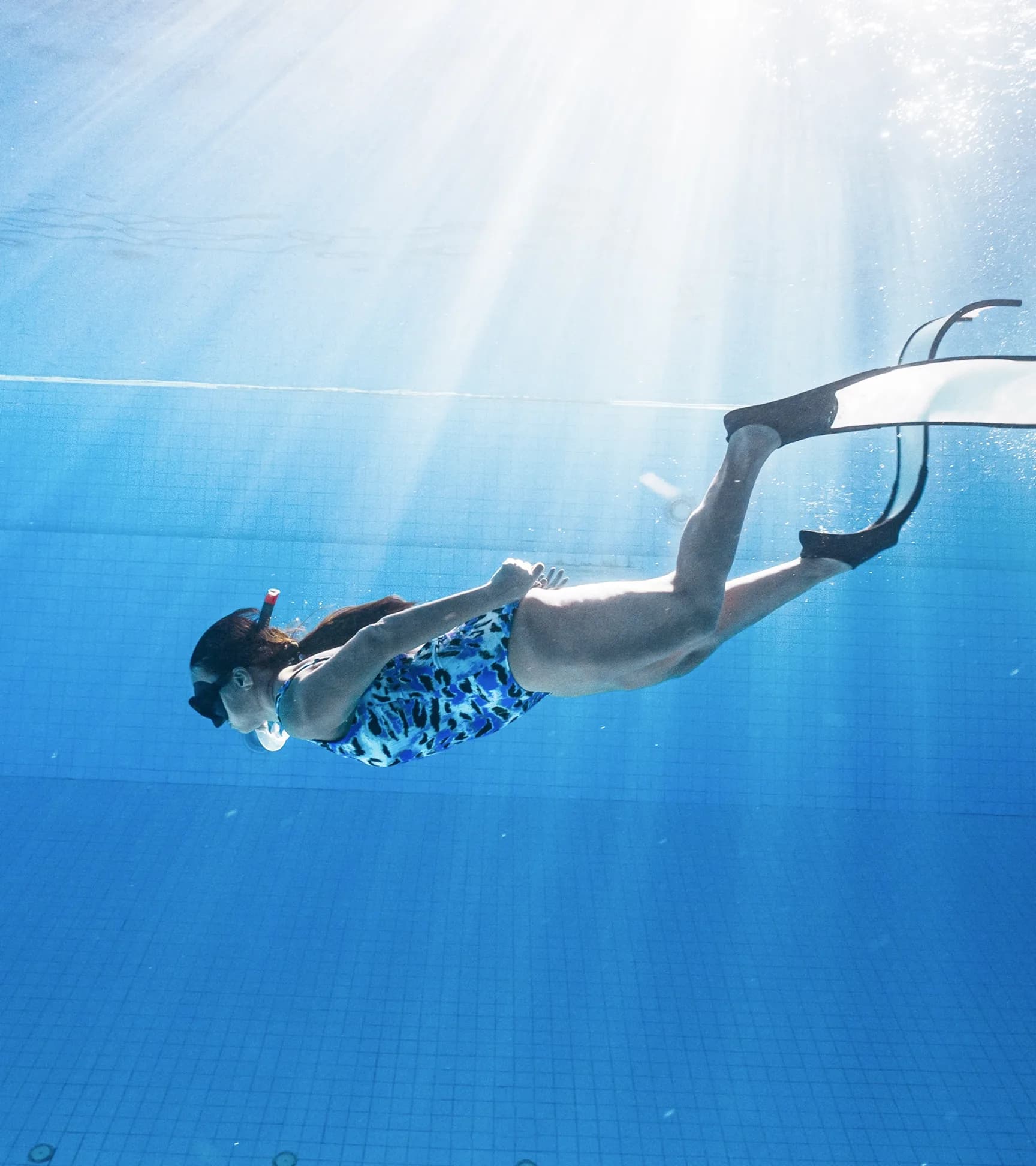Snorkeller diving through clear sunlit water