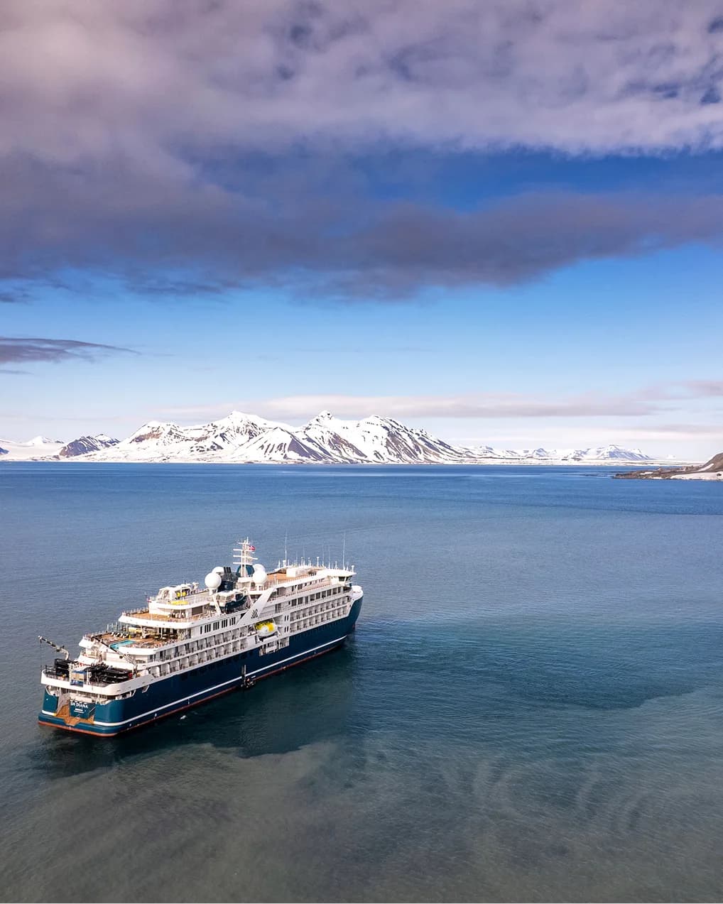 Expedition ship at anchor in front of snow-covered mountains