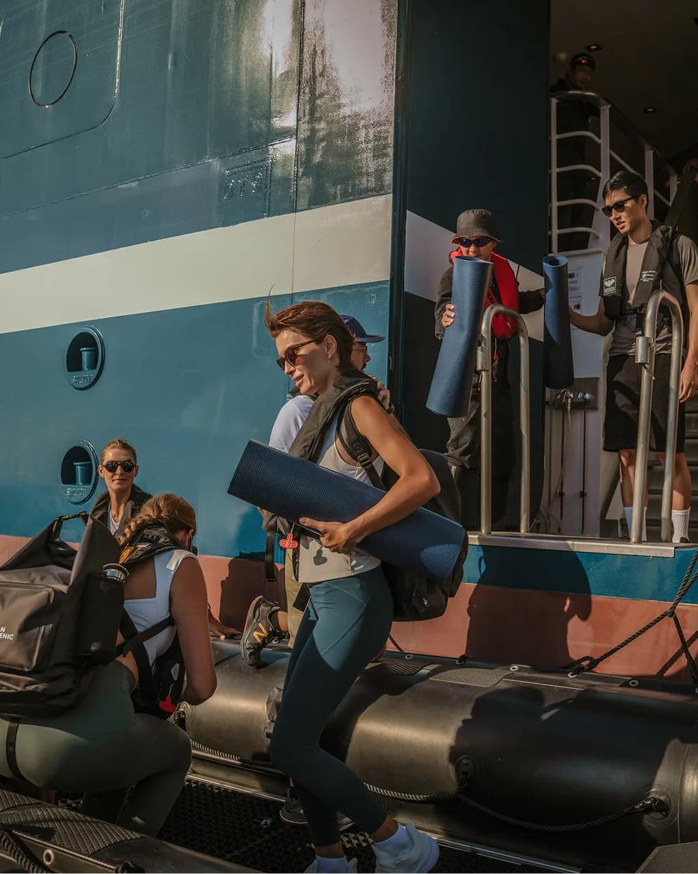 Guests carrying expedition kit down to a Zodiac from the ship's side door