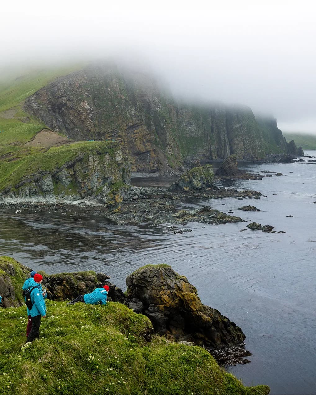 Guests photographing a cliff-lined coast on a shore hike