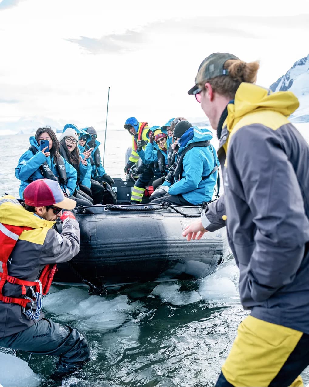 Expedition team steadying a Zodiac full of guests at the ice edge